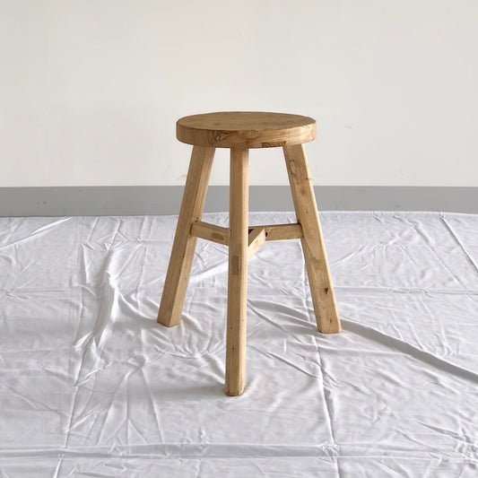 Wooden stool on a white floor with a plain background
